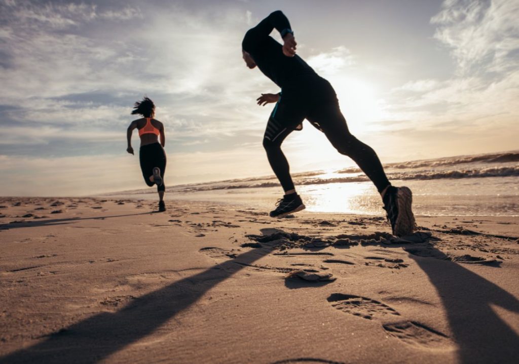 hai người đang chạy đuổi nhau trên bờ biển