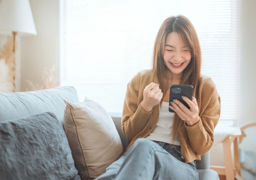 người phụ nữ xem điện thoại, cười tươi
