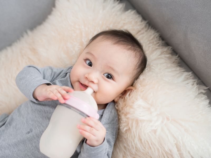 bé gái cầm bình sữa